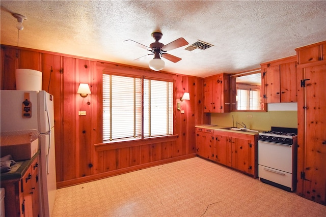 kitchen featuring a wealth of natural light, white appliances, a textured ceiling, and ceiling fan