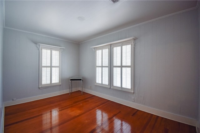 spare room with wood walls, hardwood / wood-style flooring, and crown molding