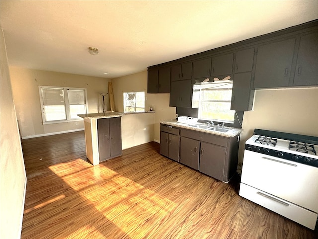 kitchen featuring kitchen peninsula, light hardwood / wood-style floors, white stove, and a breakfast bar