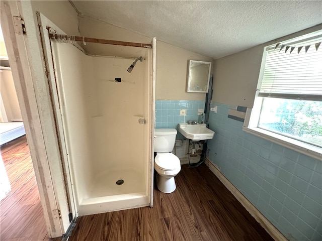 bathroom featuring walk in shower, hardwood / wood-style flooring, a textured ceiling, toilet, and tile walls