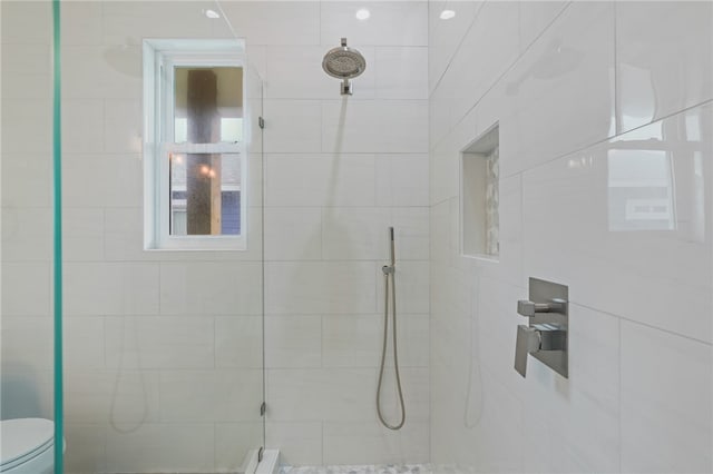 bathroom featuring tiled shower and toilet