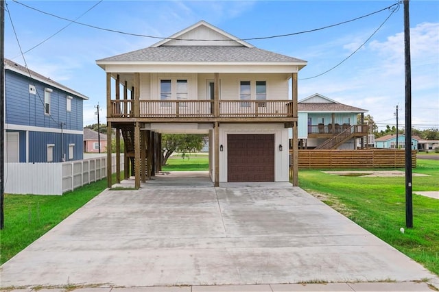 1007 S Live Oak St, Rockport, TX 78382 - raised beach house with driveway, a garage, a shingled roof, stairway, and covered porch