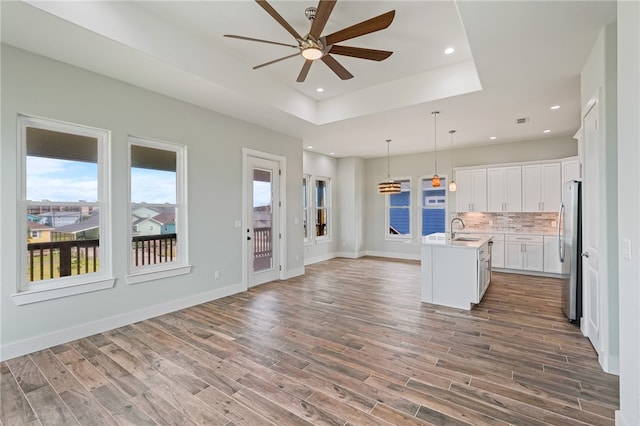 kitchen featuring stainless steel refrigerator, dark hardwood / wood-style flooring, sink, white cabinets, and a kitchen island with sink