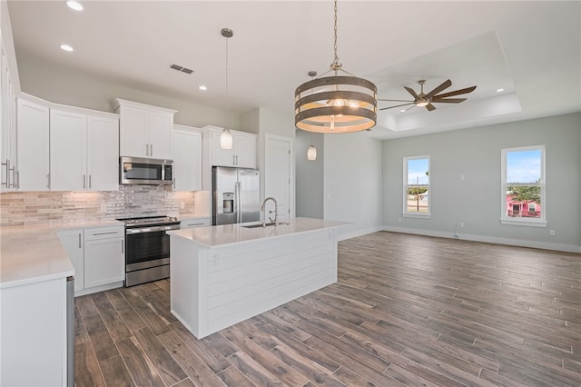 kitchen with dark wood-type flooring, white cabinetry, an island with sink, and stainless steel appliances