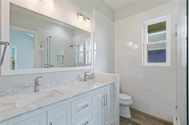 bathroom featuring plenty of natural light, hardwood / wood-style floors, vanity, an enclosed shower, and toilet