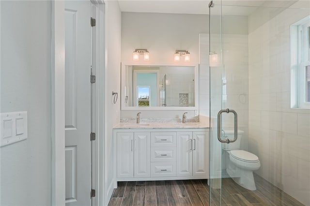 bathroom featuring wood-type flooring, vanity, toilet, and a shower with door