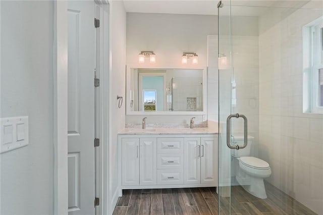 1007 S Live Oak St, Rockport, TX 78382 - bathroom with wood tiled floors, double vanity, toilet, and a stall shower
