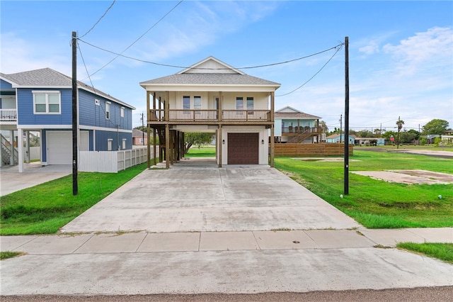 raised beach house featuring a front yard, a garage, and covered porch