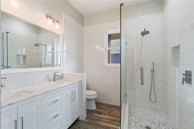 bathroom featuring hardwood / wood-style floors, vanity, toilet, and a shower with door