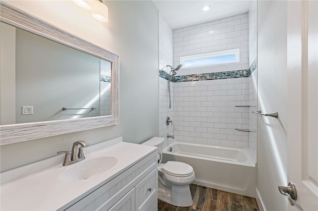 full bathroom featuring hardwood / wood-style floors, tiled shower / bath, toilet, and vanity