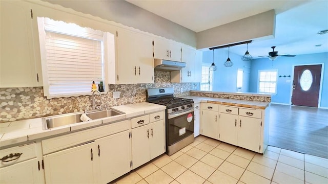 134 W C Ave, Kingsville, TX 78363 - kitchen with gas range, under cabinet range hood, a peninsula, backsplash, and ceiling fan