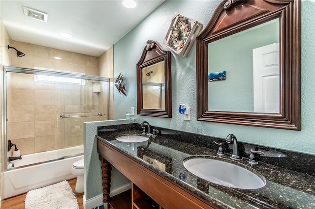 full bathroom featuring toilet, vanity, hardwood / wood-style floors, and enclosed tub / shower combo