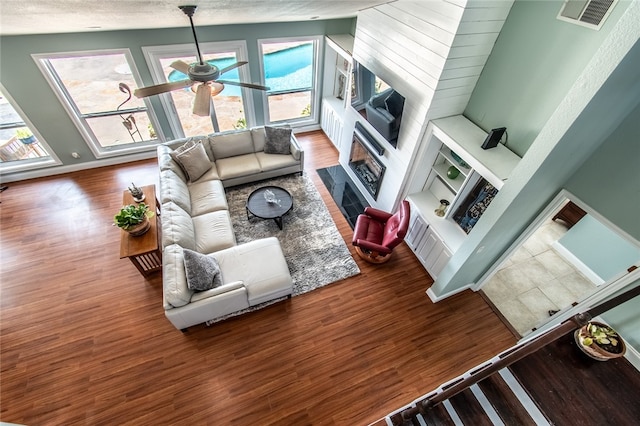 living room with a textured ceiling, high vaulted ceiling, hardwood / wood-style flooring, and ceiling fan