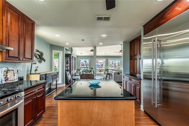 kitchen with dark wood-type flooring, a kitchen island, and appliances with stainless steel finishes