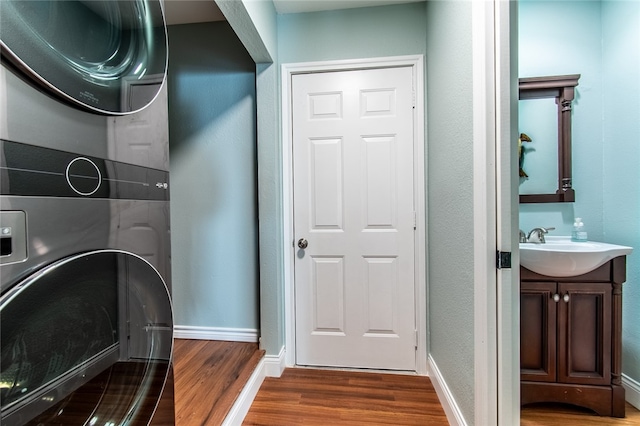 laundry area with dark hardwood / wood-style flooring, sink, and stacked washer and clothes dryer