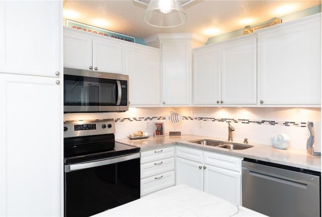 kitchen with sink, light stone counters, decorative backsplash, white cabinets, and appliances with stainless steel finishes