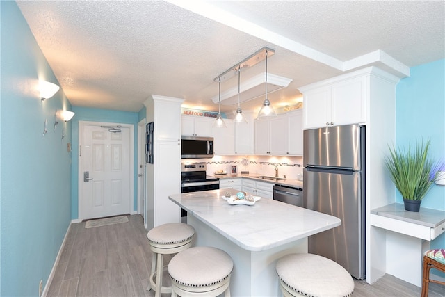 kitchen with decorative backsplash, a textured ceiling, stainless steel appliances, decorative light fixtures, and white cabinets