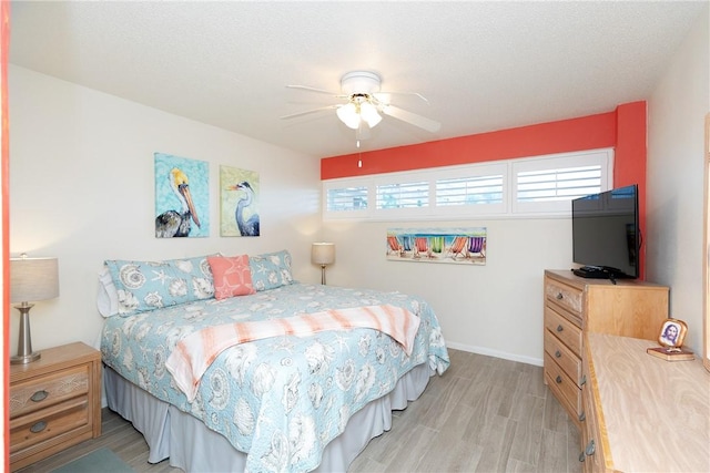 bedroom featuring ceiling fan, light wood-type flooring, and a textured ceiling