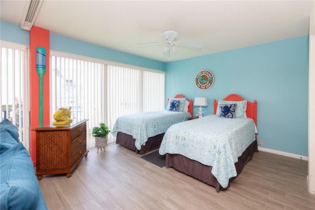 bedroom featuring ceiling fan, light hardwood / wood-style floors, and multiple windows