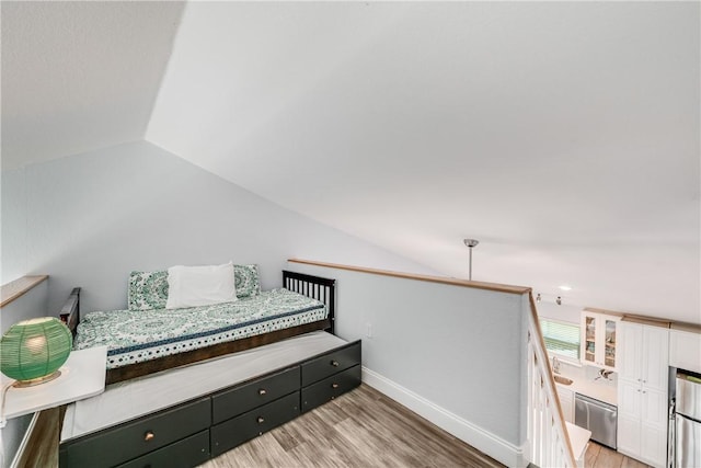 800 Beach Access Road 1a 804, Port Aransas, TX 78373 - bedroom with vaulted ceiling, light wood-style flooring, baseboards, and freestanding refrigerator