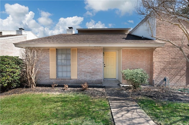 view of front of house featuring a shingled roof and brick siding