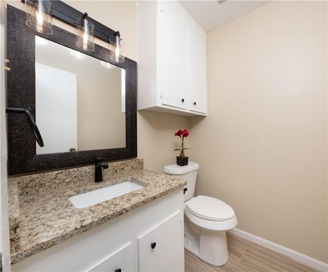 bathroom with baseboards, vanity, toilet, and wood finished floors