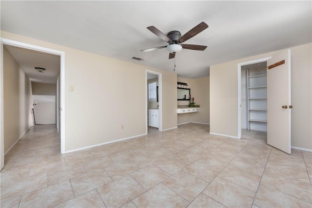 unfurnished bedroom with light tile patterned floors, a walk in closet, visible vents, and baseboards