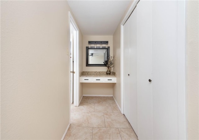 corridor with baseboards and light tile patterned floors