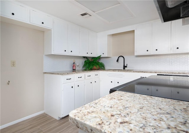 kitchen featuring light wood-style floors, white cabinetry, visible vents, and decorative backsplash