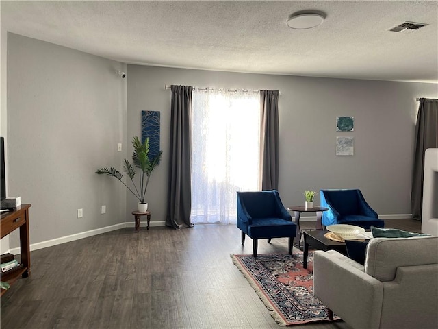 living room with a textured ceiling and dark wood-type flooring