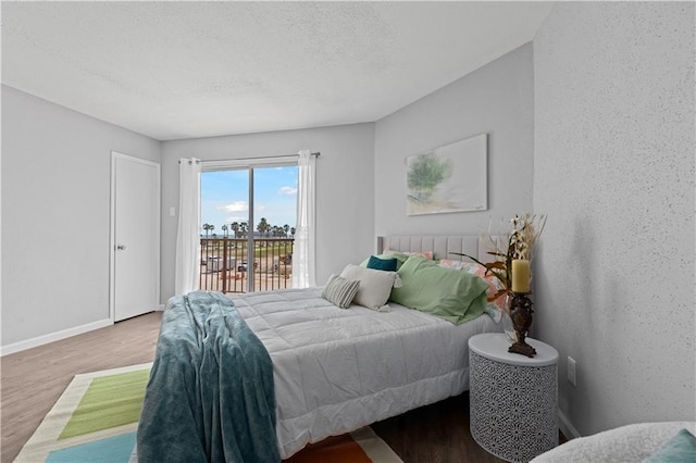 bedroom featuring wood-type flooring, a textured ceiling, and access to outside