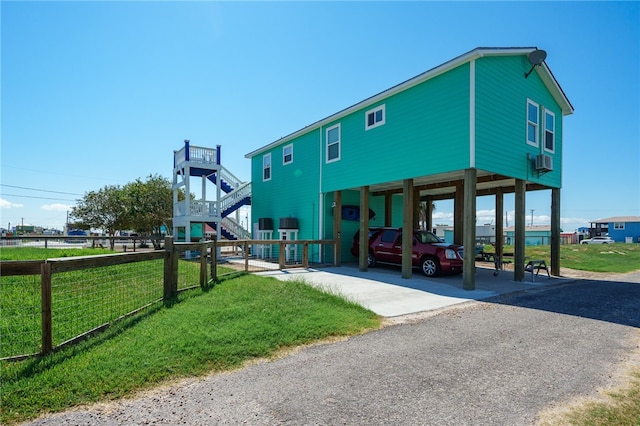 exterior space featuring a carport, a front yard, and cooling unit