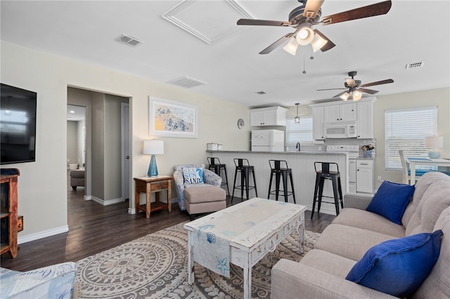 living room with dark wood-type flooring and ceiling fan