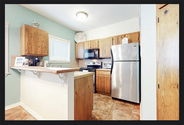 kitchen featuring kitchen peninsula, light tile patterned floors, electric range oven, a breakfast bar, and stainless steel refrigerator