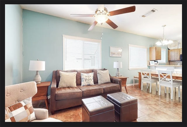 tiled living room featuring ceiling fan with notable chandelier