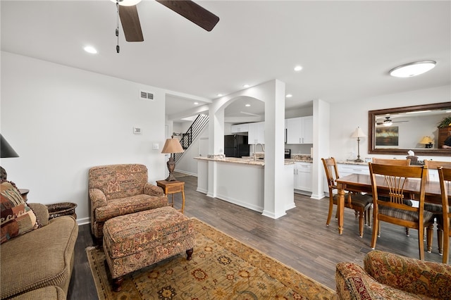 living room with dark wood-type flooring and ceiling fan