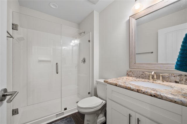 bathroom with an enclosed shower, vanity, and toilet