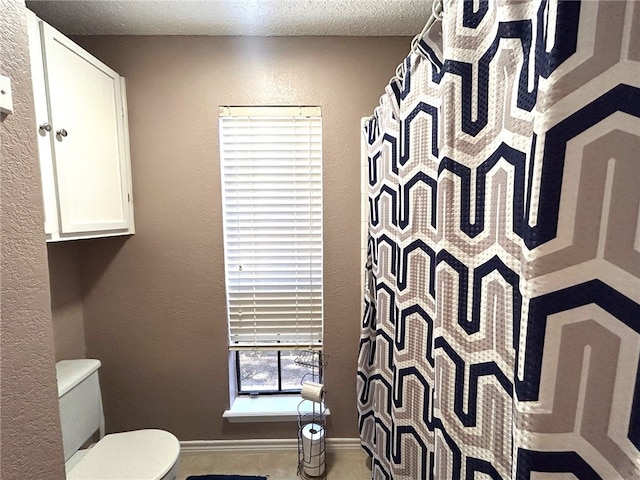 bathroom featuring toilet, a textured ceiling, and walk in shower