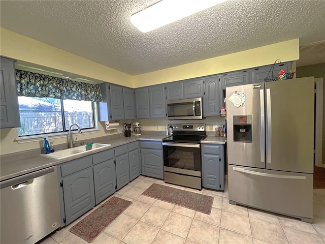 kitchen with gray cabinetry, light tile patterned flooring, sink, and appliances with stainless steel finishes