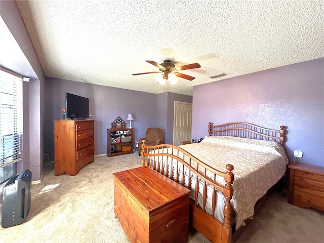 bedroom with ceiling fan, light colored carpet, and a textured ceiling