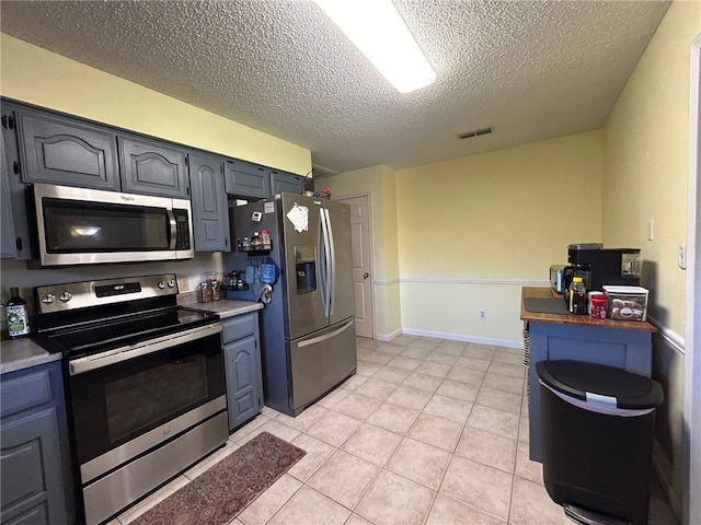 kitchen with light tile patterned floors, stainless steel appliances, and a textured ceiling