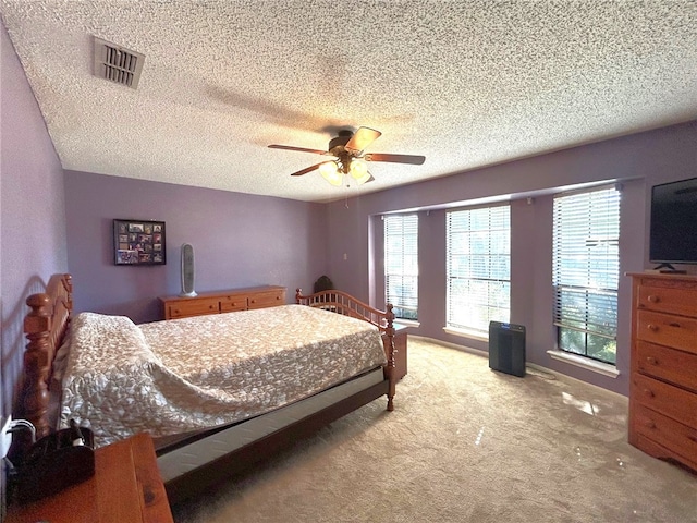 bedroom featuring ceiling fan, light colored carpet, and a textured ceiling