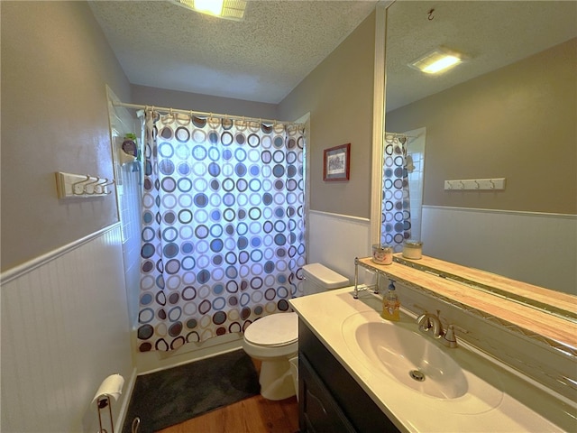 full bathroom featuring vanity, a textured ceiling, shower / tub combo with curtain, hardwood / wood-style floors, and toilet