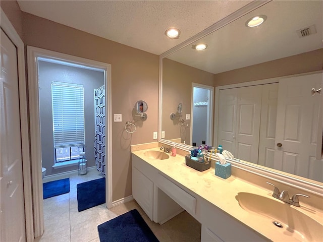 bathroom with tile patterned flooring, vanity, a textured ceiling, and toilet