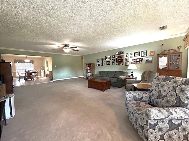 living room featuring ceiling fan, carpet floors, a textured ceiling, and ornamental molding