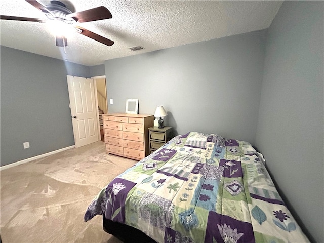 carpeted bedroom with ceiling fan and a textured ceiling