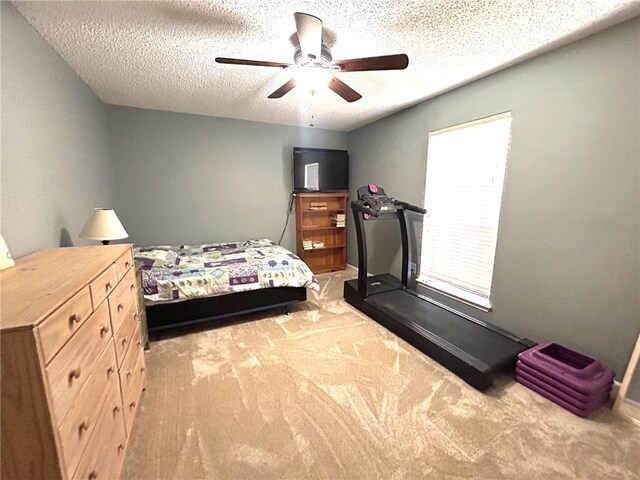 carpeted bedroom featuring ceiling fan and a textured ceiling