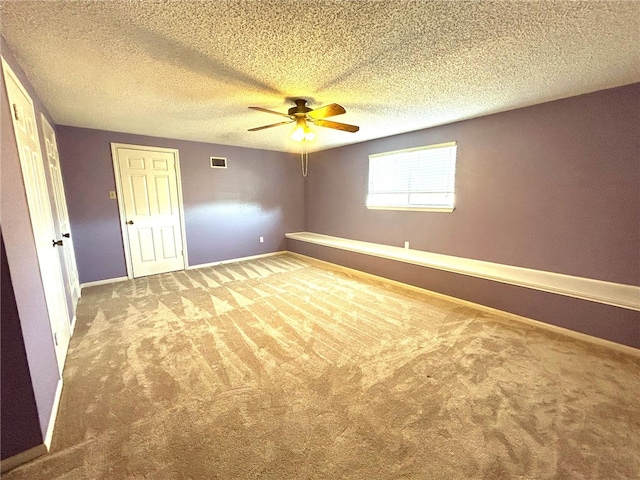 carpeted spare room featuring ceiling fan and a textured ceiling