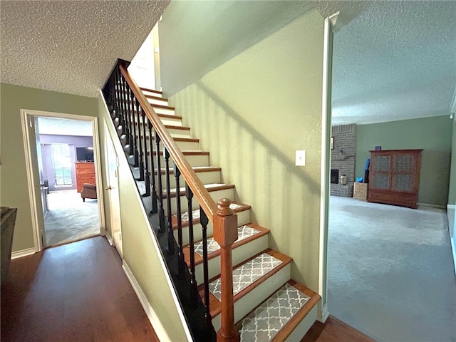 stairs with a fireplace, a textured ceiling, and carpet floors