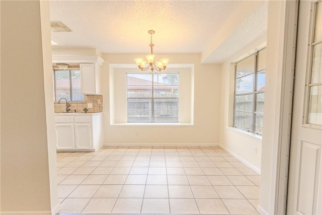 2721 Tumbleweed Dr, Corpus Christi, TX 78410 - unfurnished dining area with a chandelier, a textured ceiling, healthy amount of natural light, and light tile patterned flooring